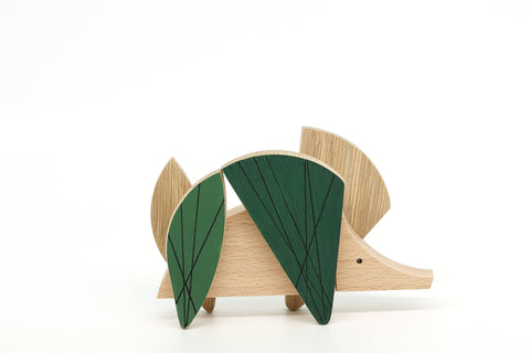 Wooden toy hedgehog with green leaves on a white background