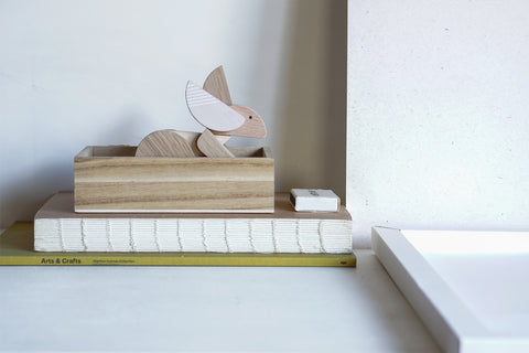 Wooden decorative rabbit on a stack of books with a plain background